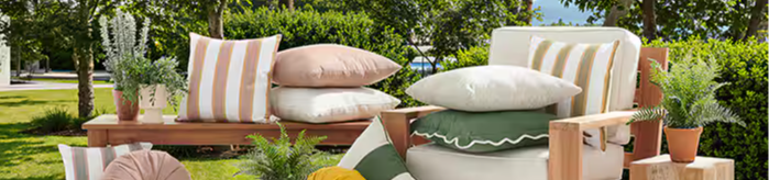 Outdoor seating area with cushions and decorative plants.