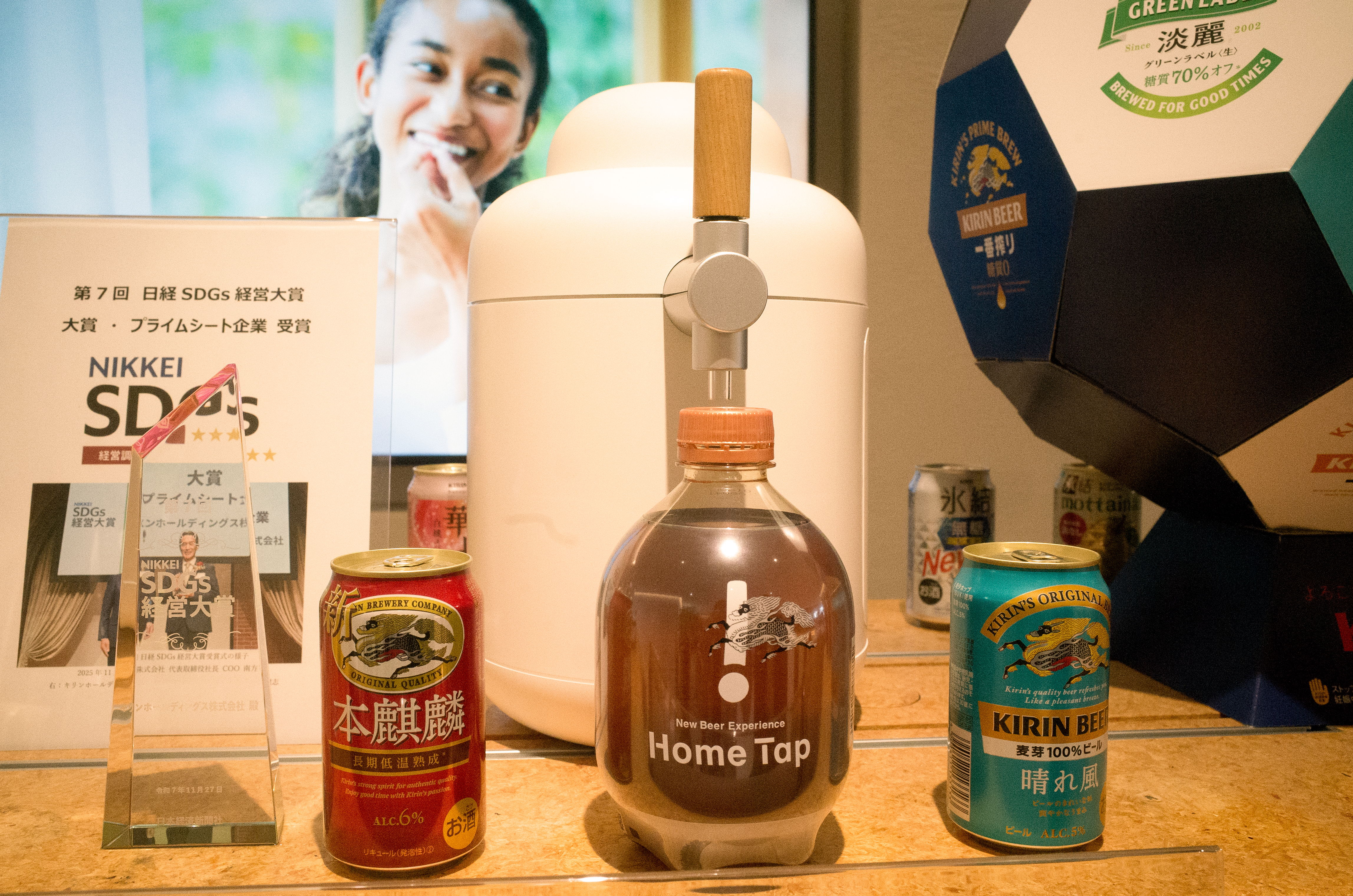 Beverages displayed on a table with a smiling person in the background.