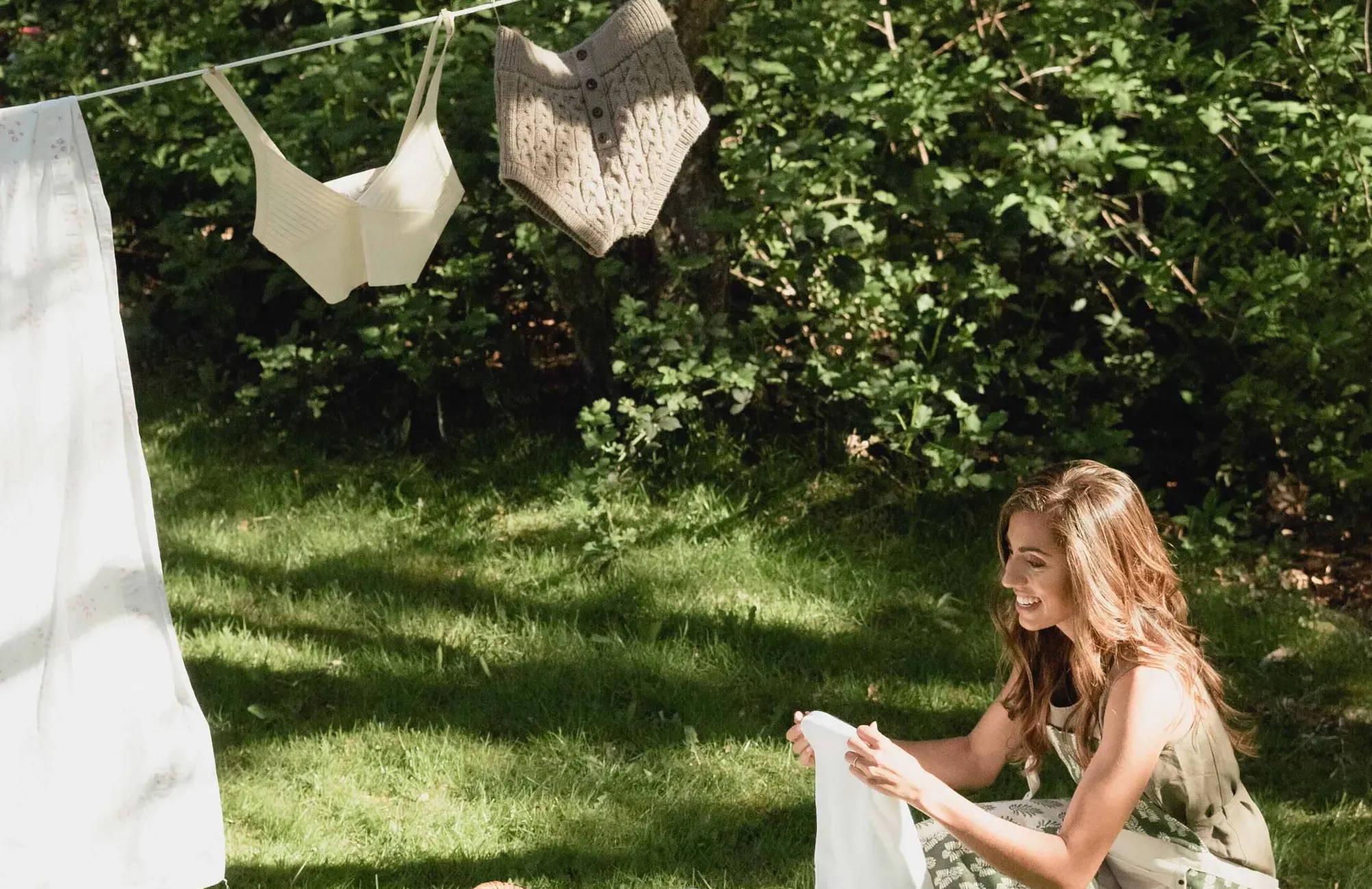 woman in apron hangs clothes from line in yard