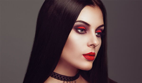 Female model with long dark hair, bold makeup, and a choker necklace.