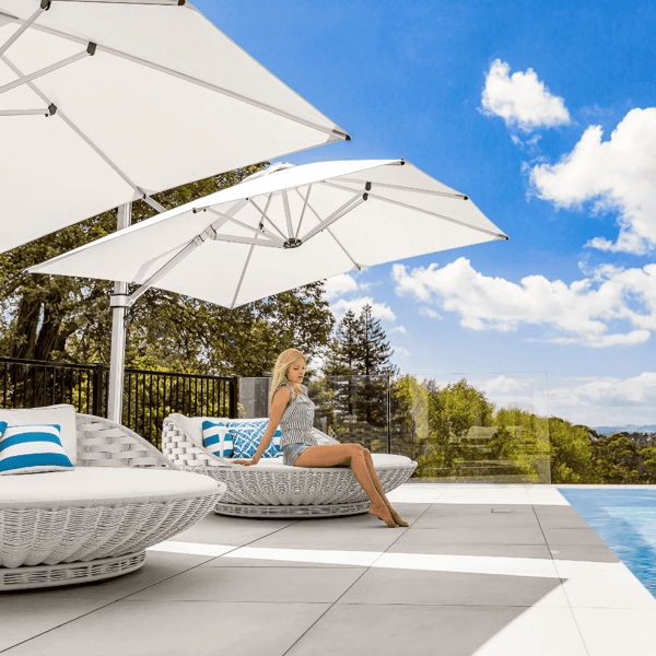 Modern poolside lounge chairs with large white cantilever umbrellas providing flexible shade for outdoor living.
