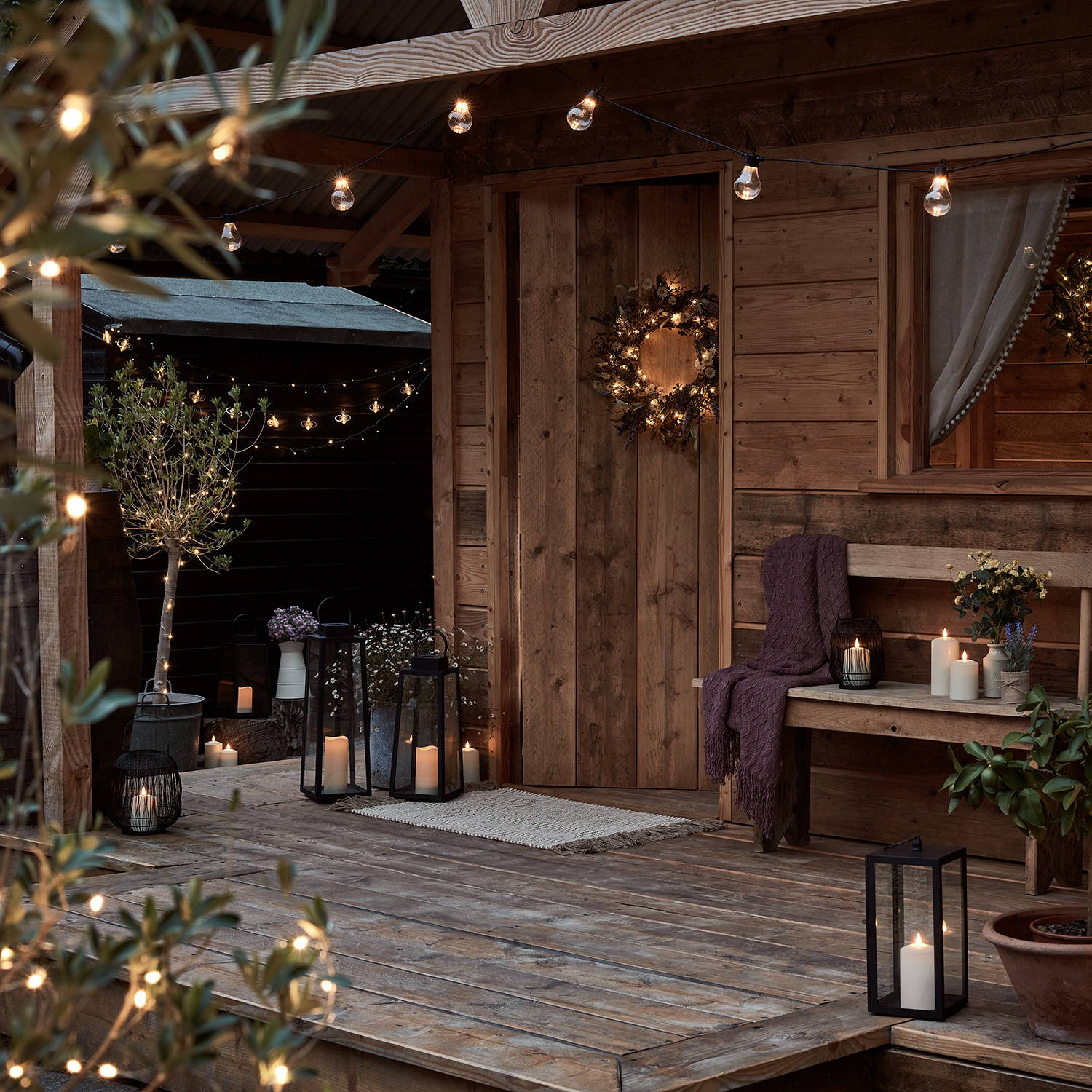 Gemütlich dekoriertes Gartenhaus aus Holz mit LED Kerzen, Gartenlaternen und Lichterketten