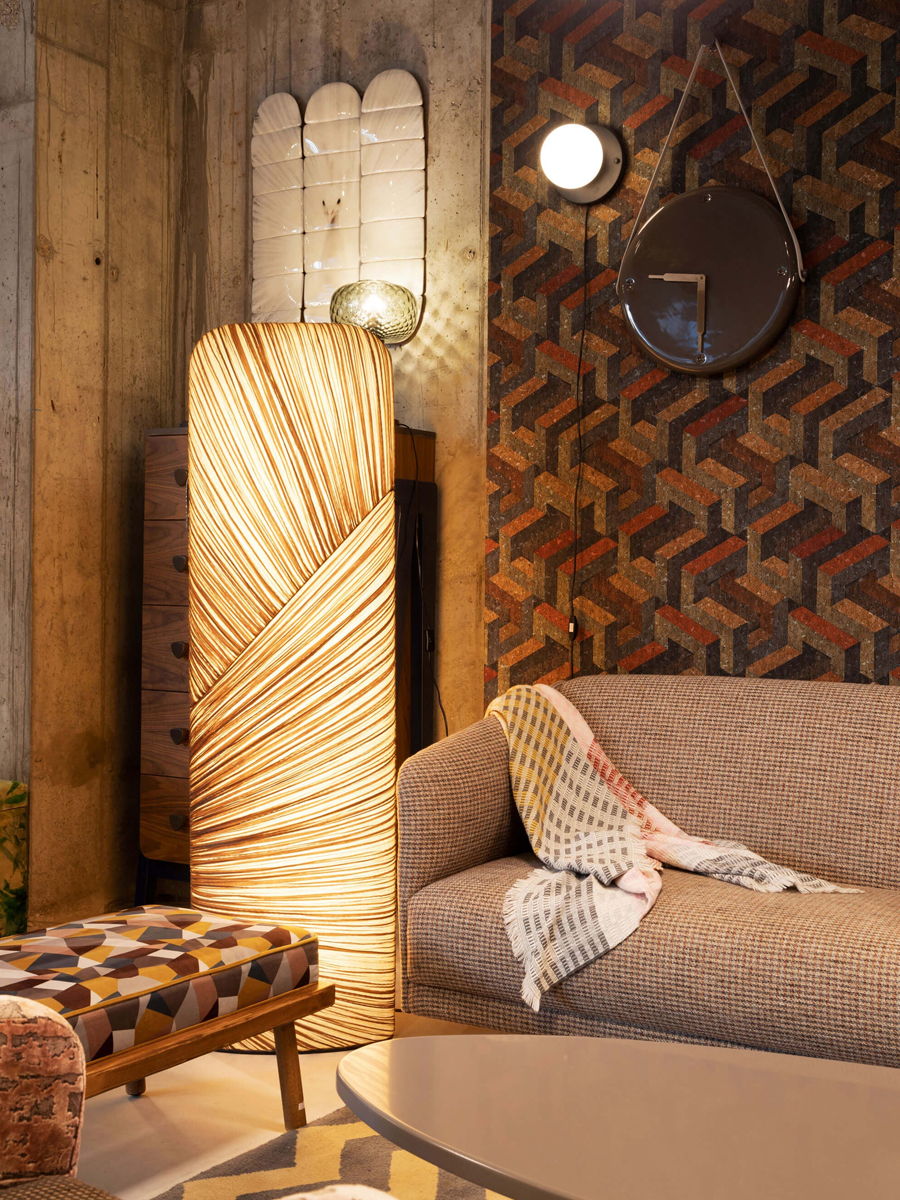 Cozy living room with patterned wallpaper, a floor lamp, and a sofa.