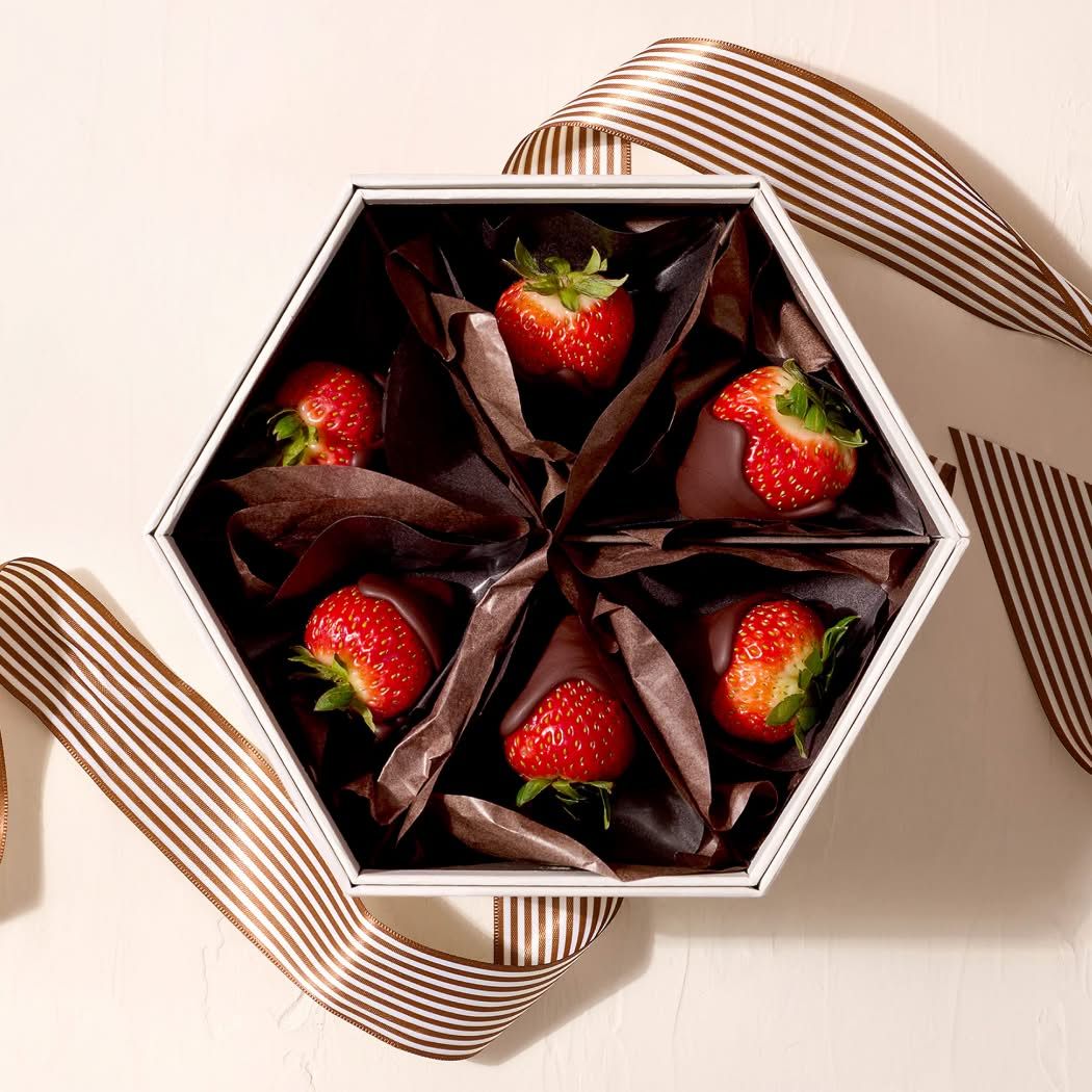 Hexagonal box with chocolate-covered strawberries and a ribbon.