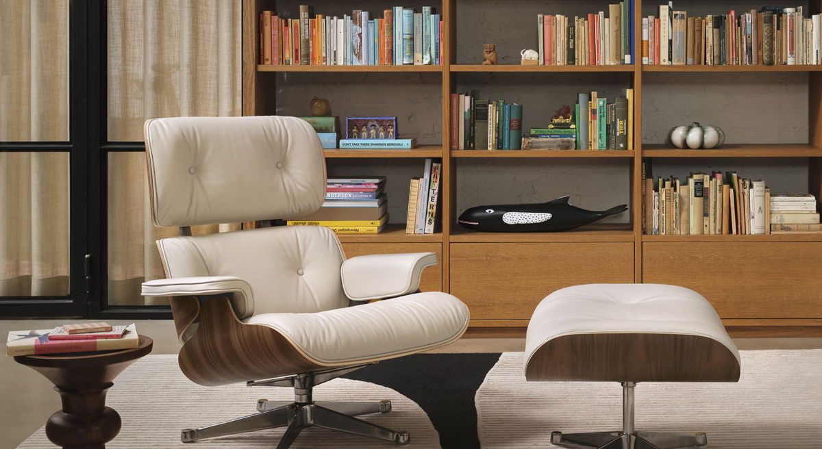 Modern living room with a stylish chair, ottoman, and bookshelf in the background.