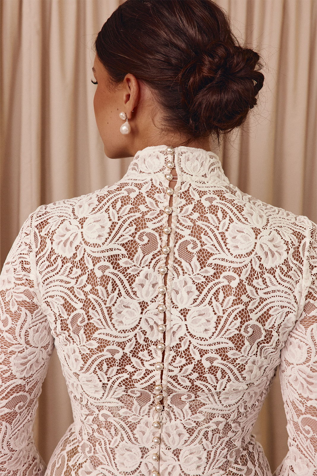 Woman in a lace dress with a high collar, seen from the back.