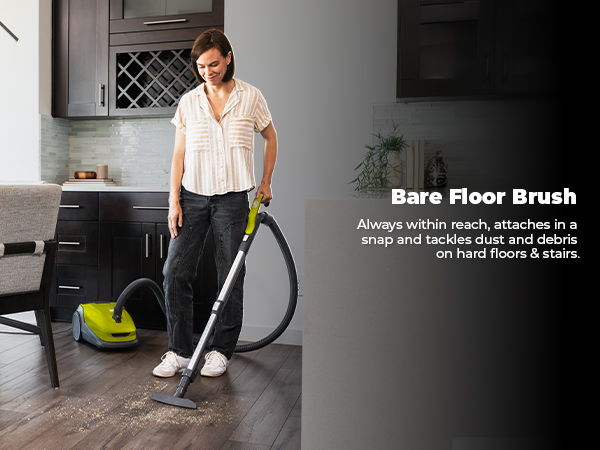 Person using a vacuum with a bare floor brush in a kitchen.