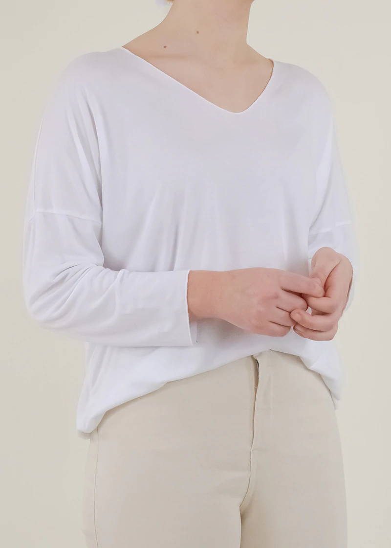 A model wearing a white long sleeve top