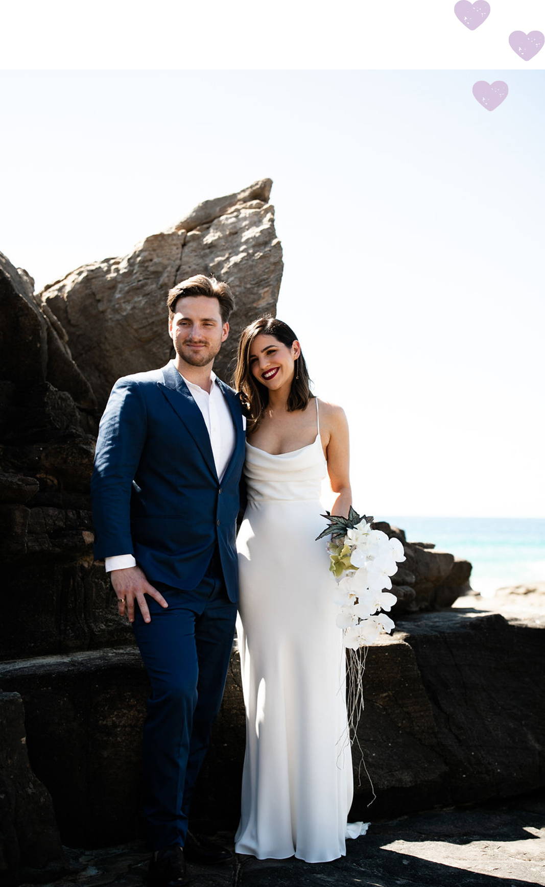 Bride wearing a white silk cowl neck dress and groom wearing navy suit