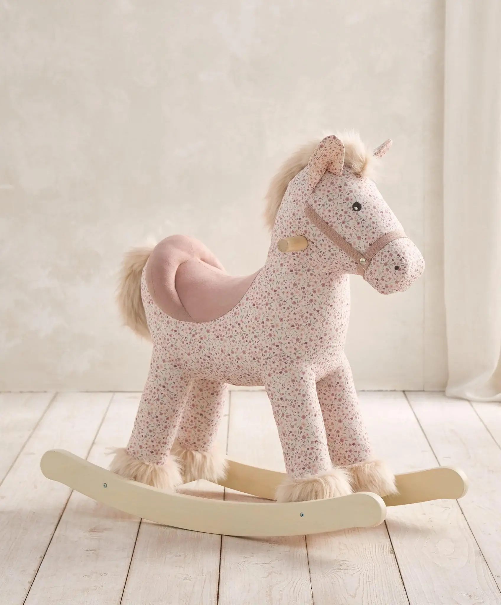 Plush rocking horse in a light, soft color on a wooden base.