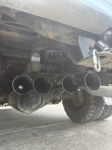 Undercarriage view of four black air horns mounted on bracket with blue air fitting near rear axle