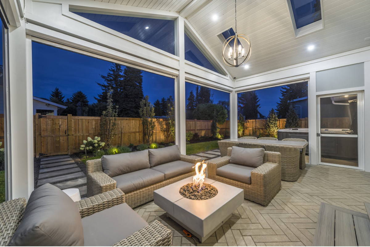 A modern square fire pit is the focal point of a covered patio sitting area.