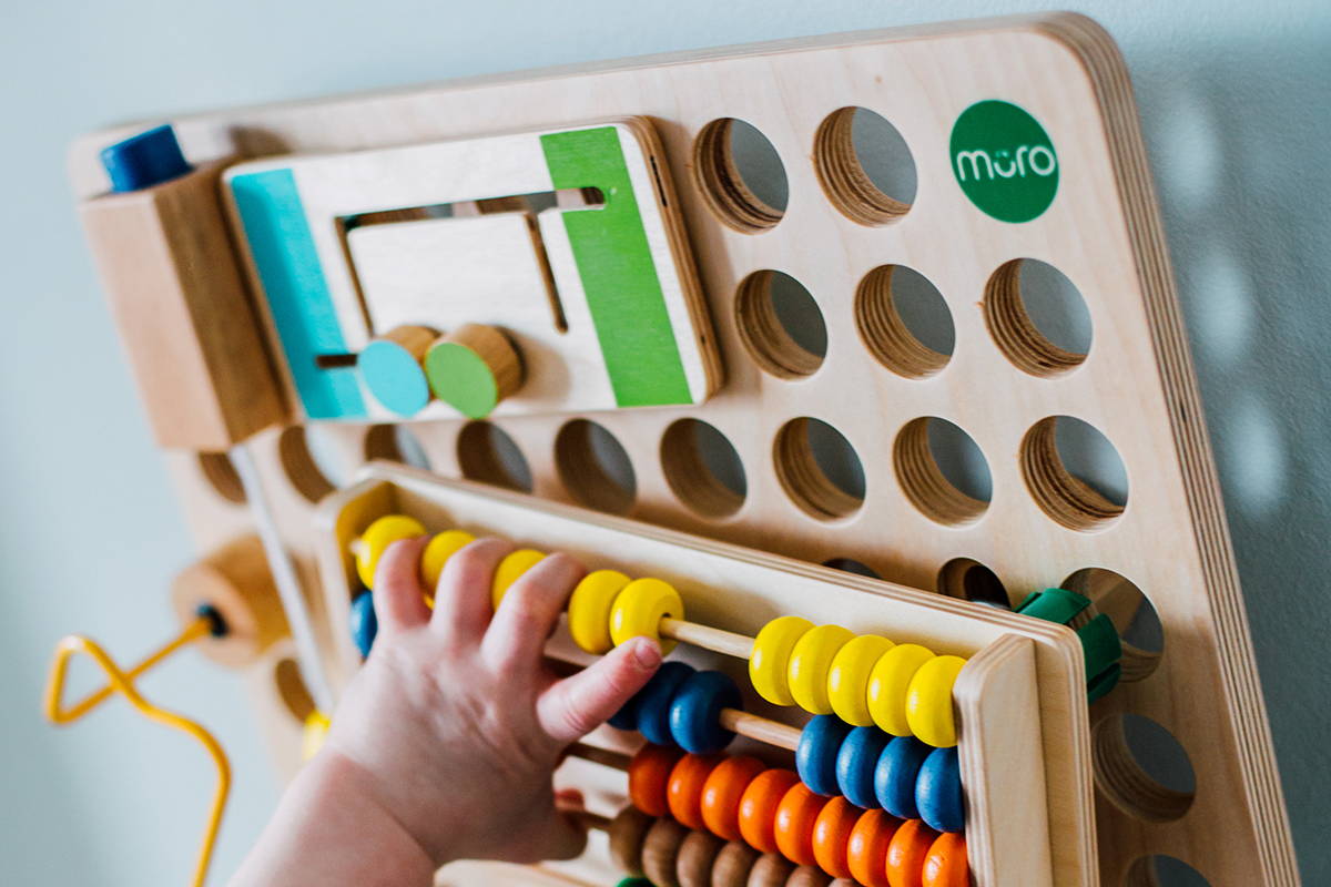 A child placing an abacus on to the muro busy board