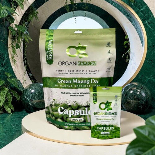 Green packaging of herbal capsules displayed on a circular pedestal surrounded by plants.