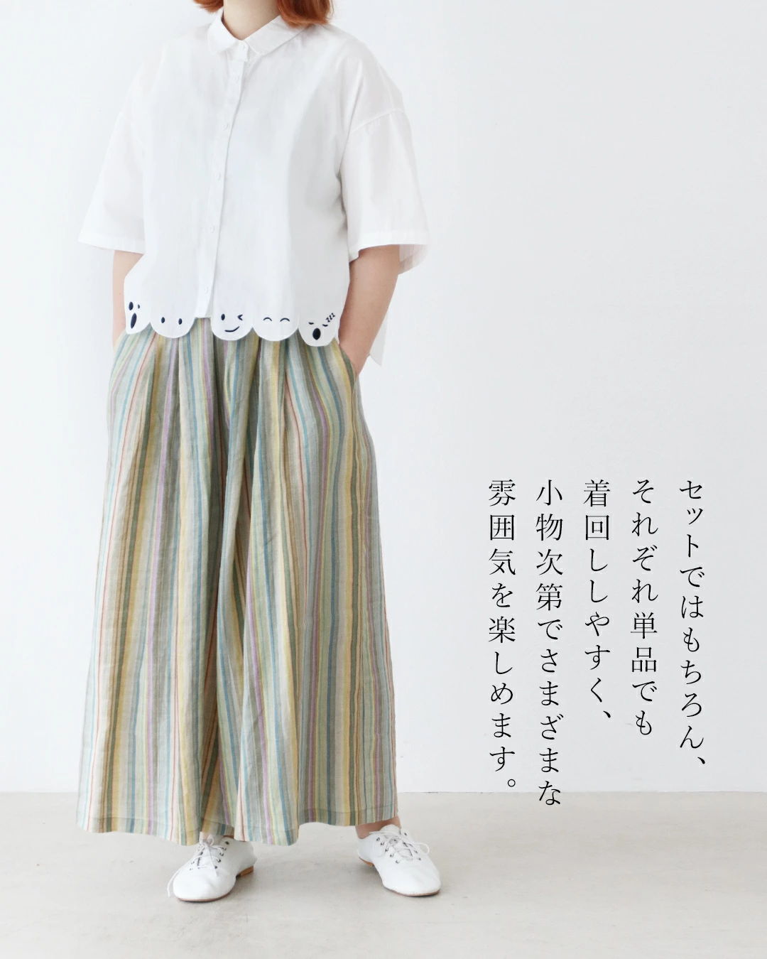 A person wearing a white blouse and striped skirt stands in a bright setting.