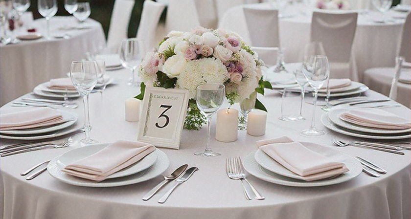 Wedding reception table with white linens and a white and pink hydrangea centerpiece.