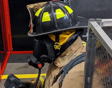 Firefighter in protective gear and mask, preparing for action.