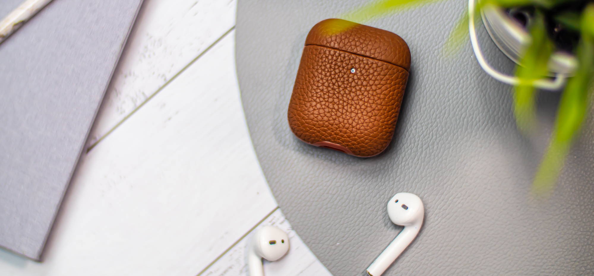 brown genuine leather airpods case flay lay on a grey wooden table top