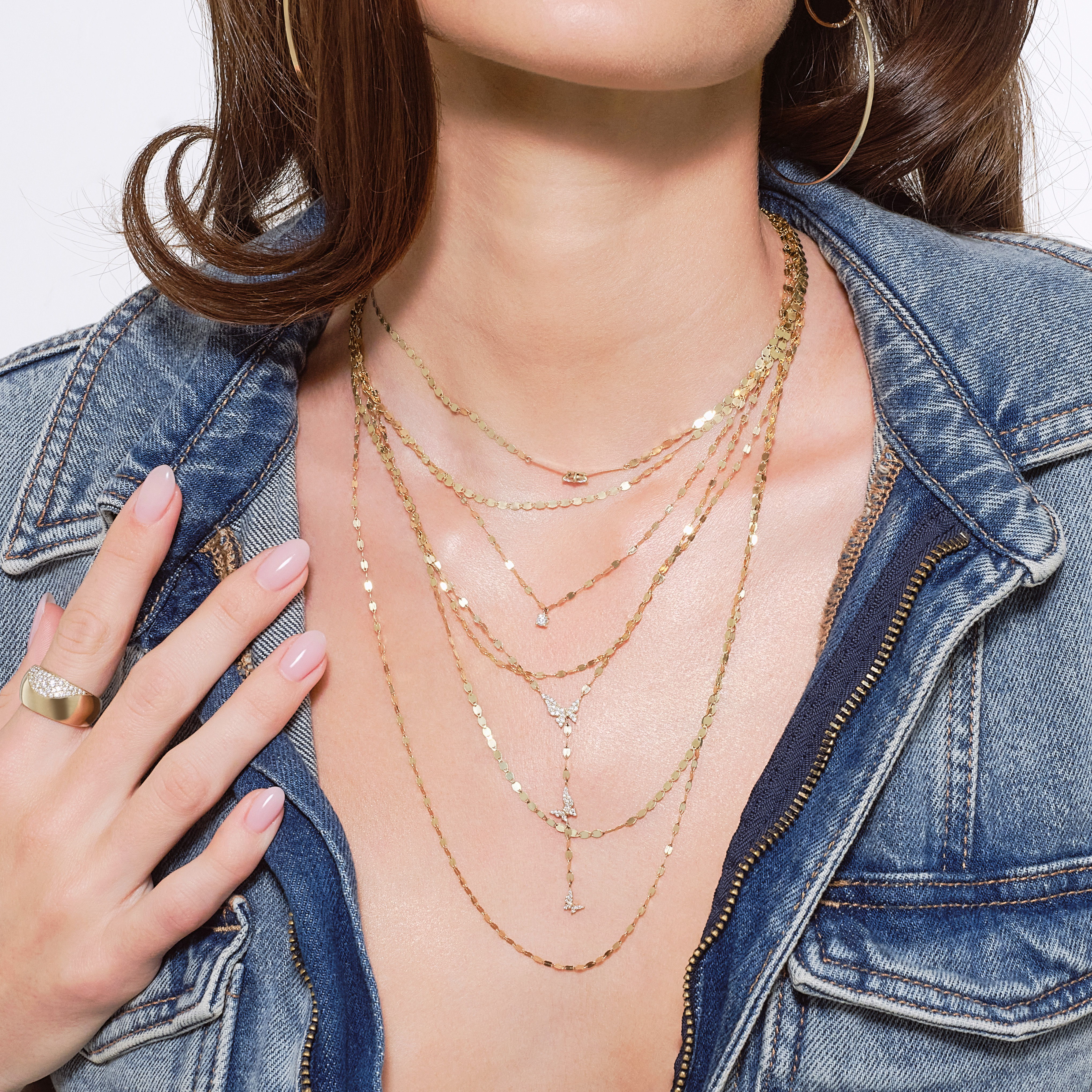 Model wearing layered yellow gold necklaces featuring the Triple Strand Blake & Petite Nude Necklace paired with delicate diamond necklaces and a yellow gold statement ring.