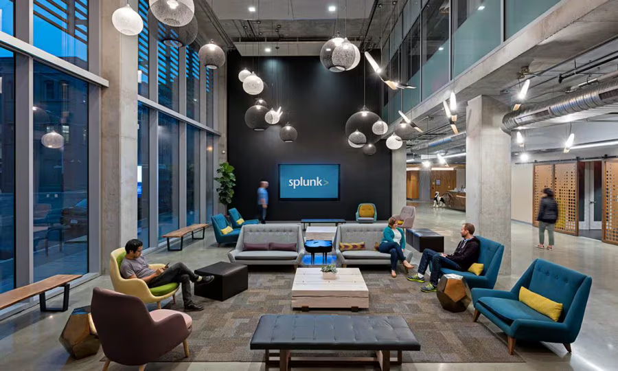 A modern office lobby with seating and a large logo on the wall.
