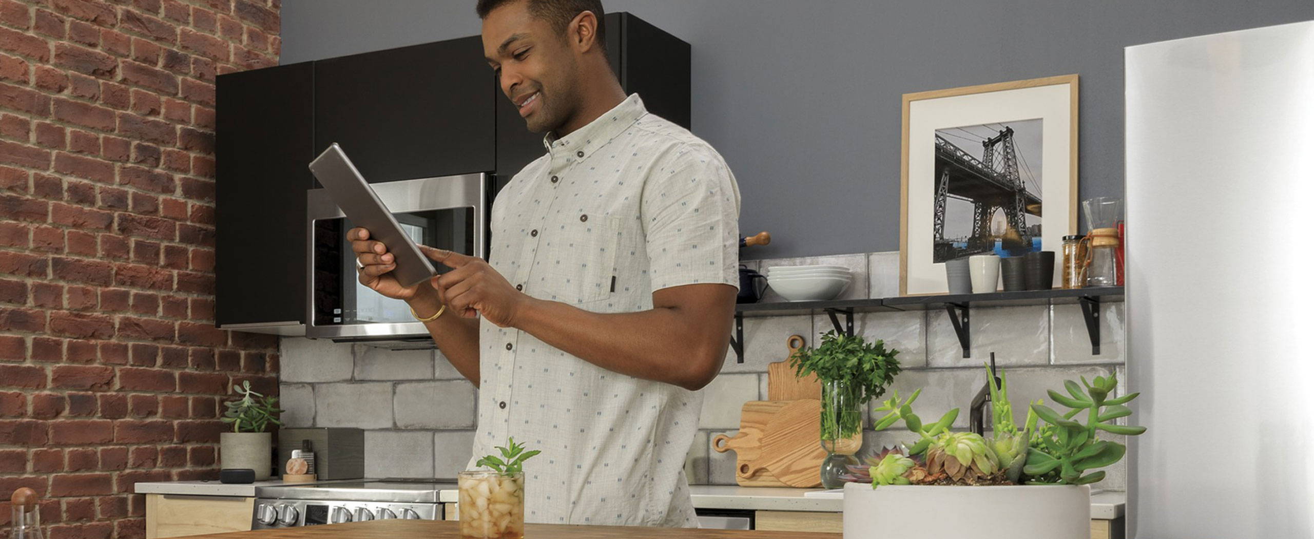 Young african american man checks his iPad while in his kitchen.a