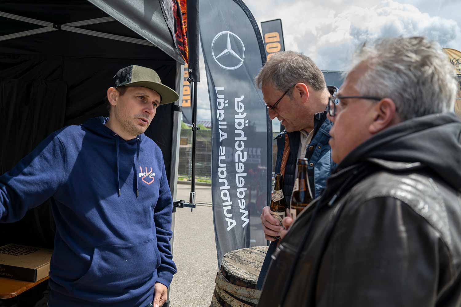 Three men engaged in conversation at an outdoor event.
