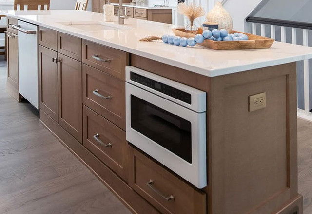 Modern kitchen island with cabinets, microwave, and decorative items on the countertop.