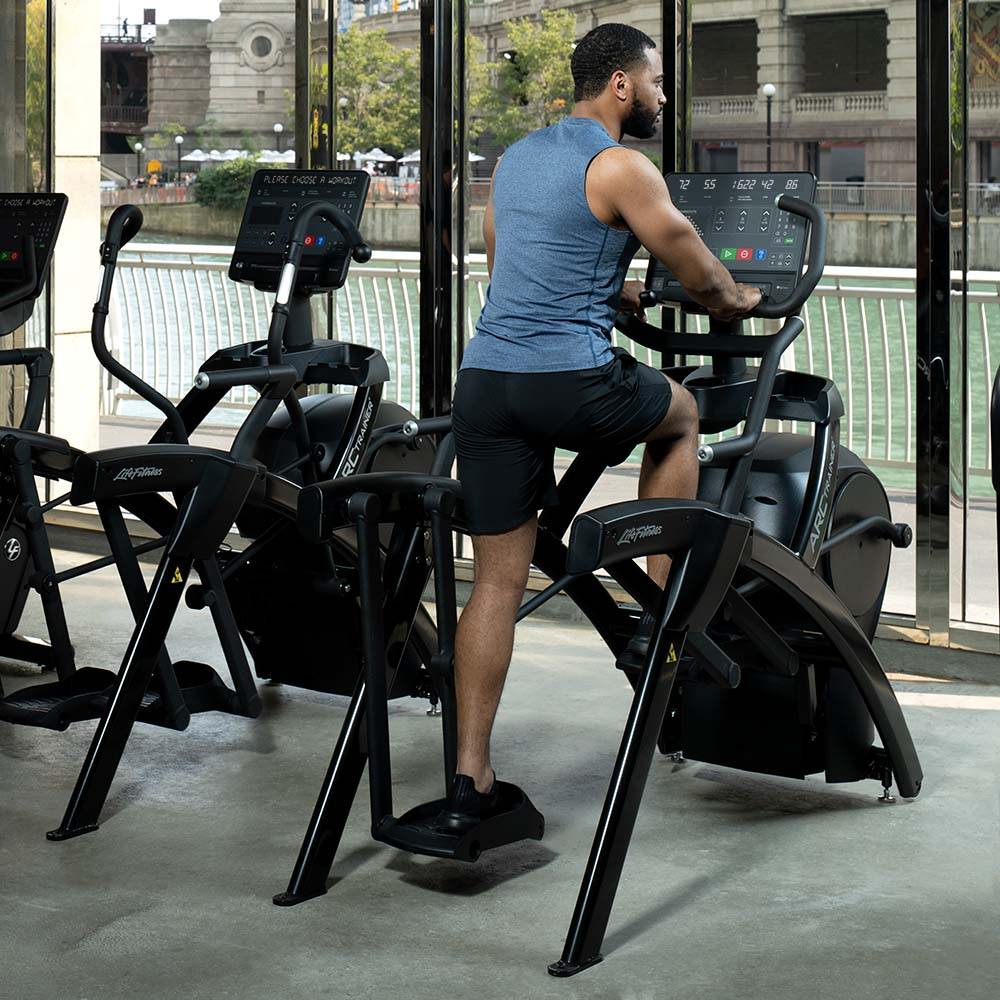 Man pedaling on Lower Body Arc Trainer with SL console, overlooking Chicago River