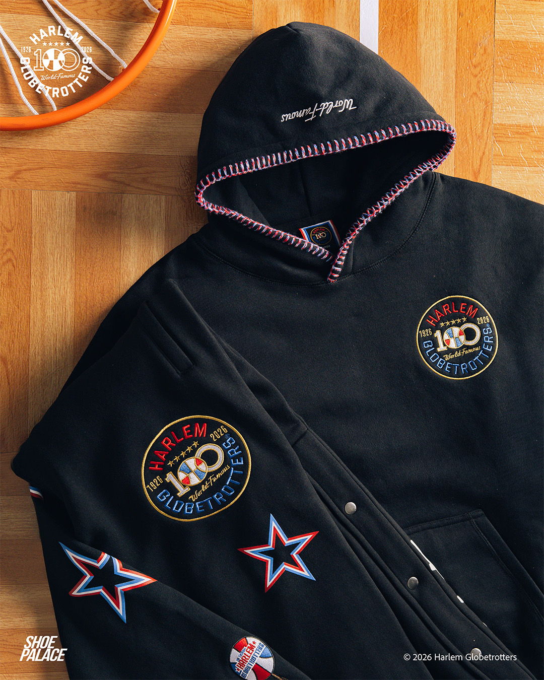 Black hoodie with colorful patches and embroidery laid on a wooden surface.