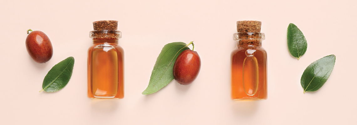 Bottles of oil, leaves, and nuts on a pastel background.