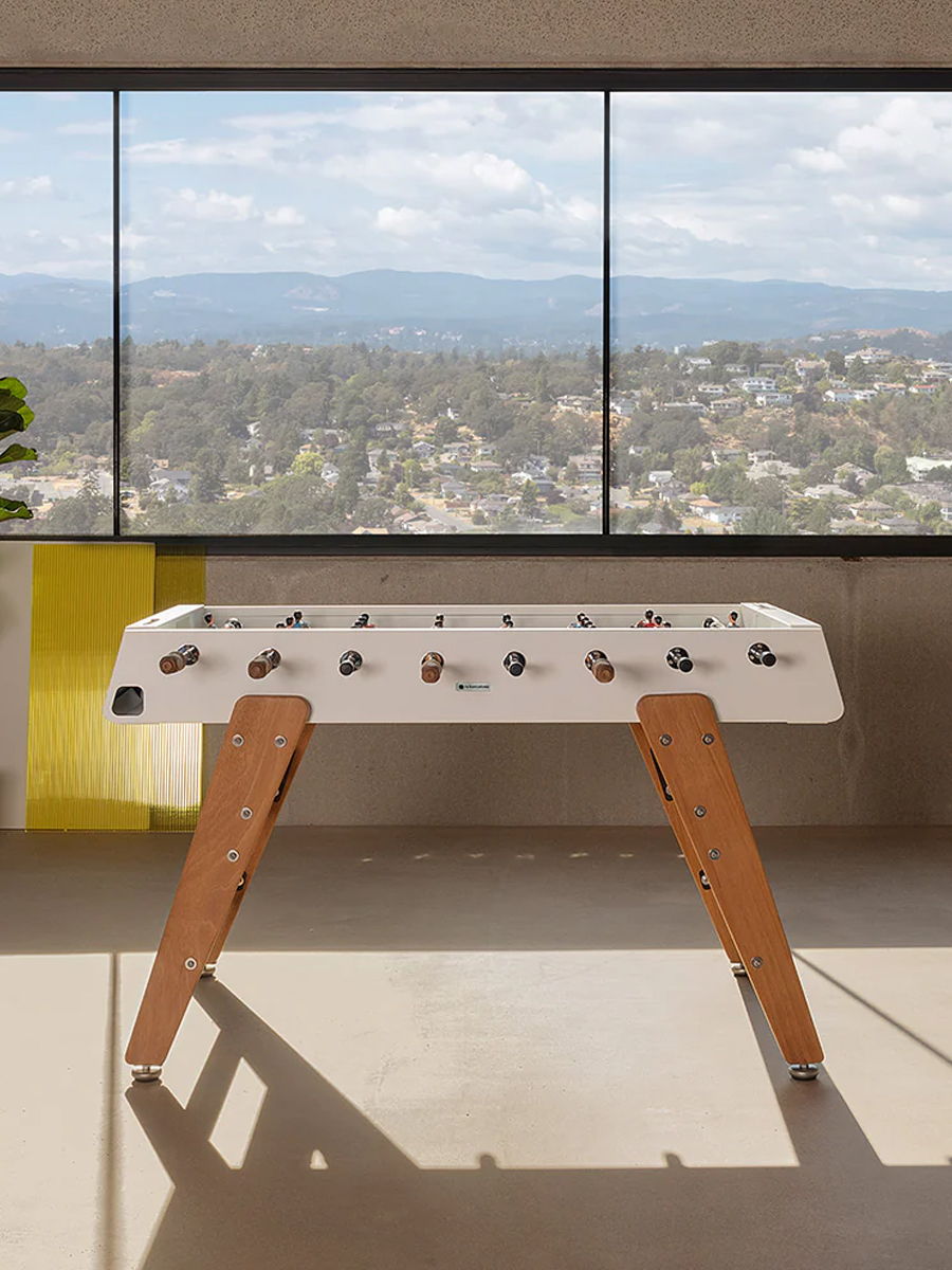 A modern interior with a foosball table and a staircase.