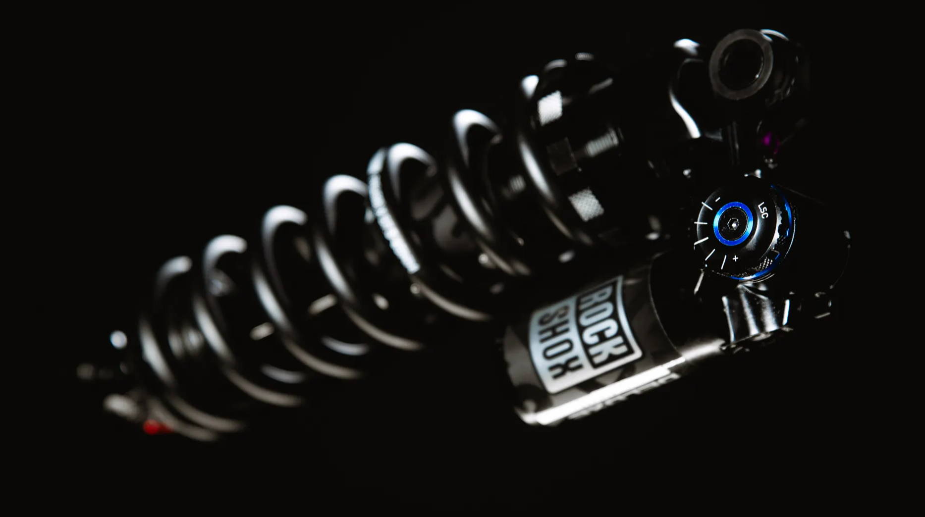 a rockshox super deluxe ultimate coil with a black spring on a black background