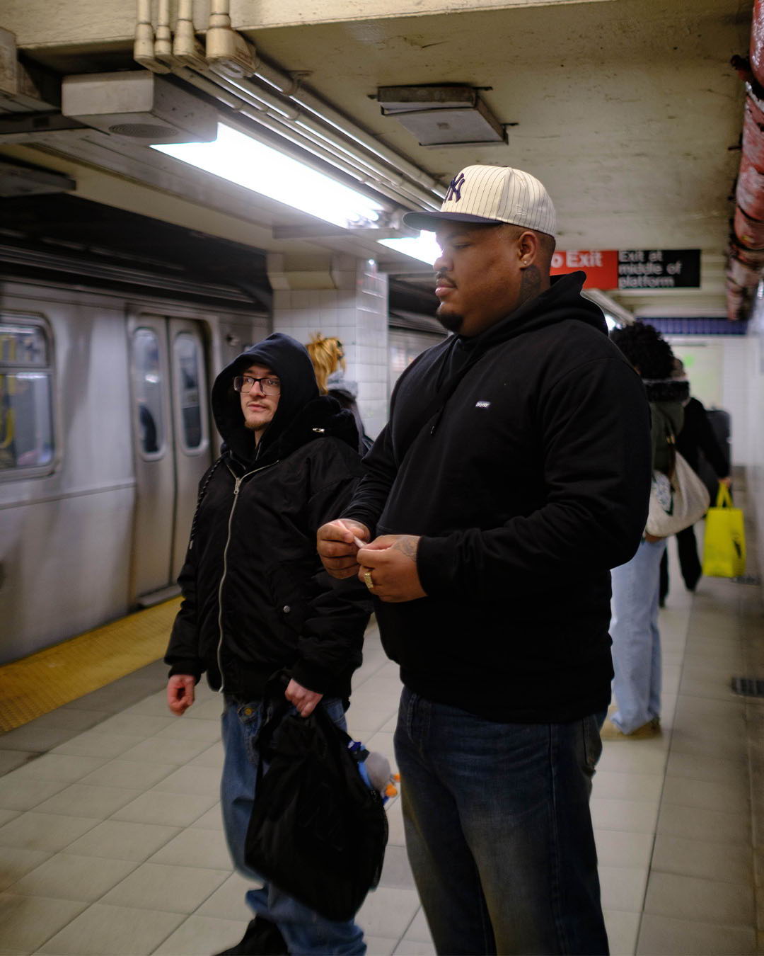 Two individuals waiting at a subway station platform.