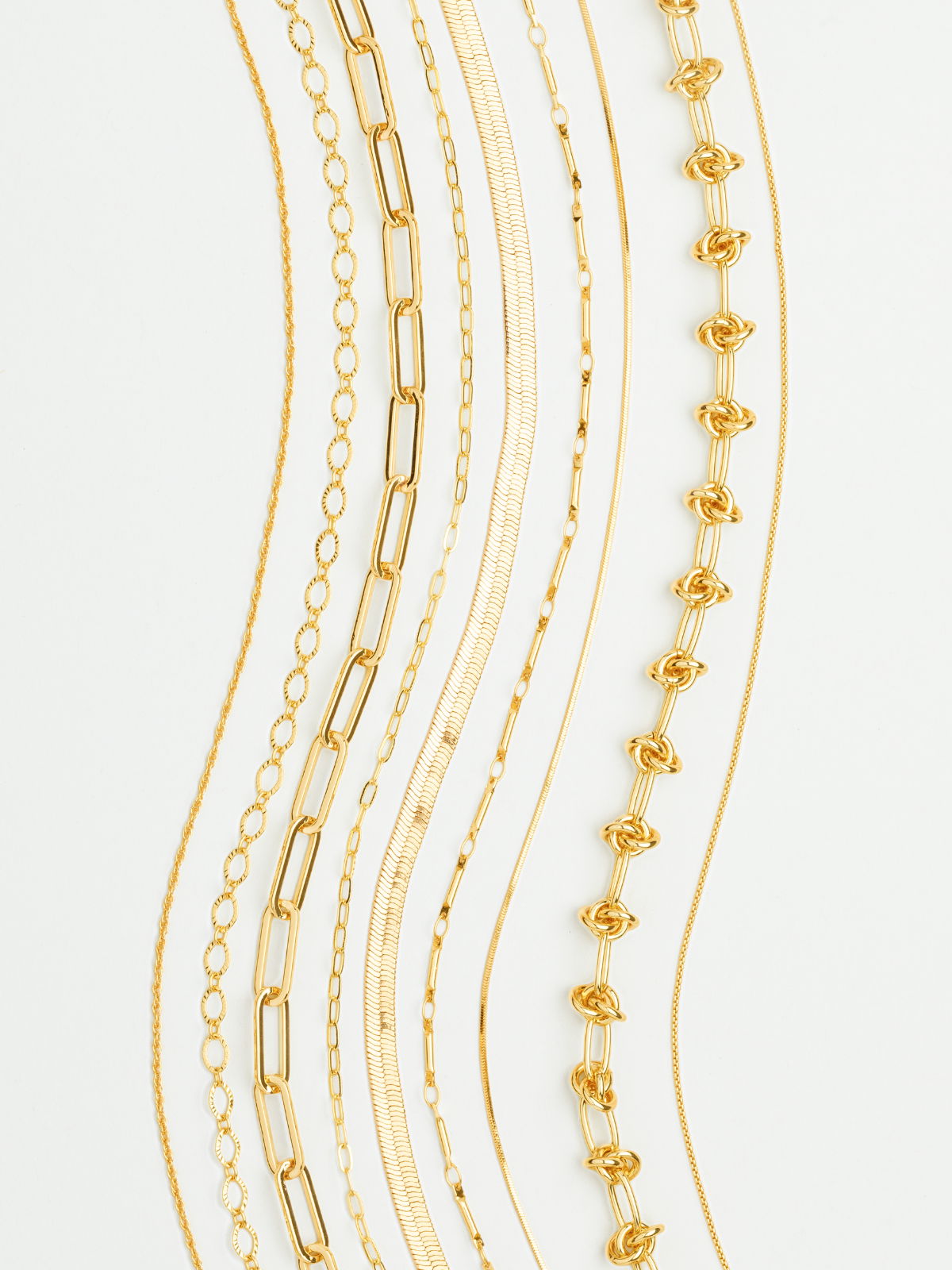 Assortment of gold necklace chains including paperclip, snake, rope, and link styles displayed vertically.