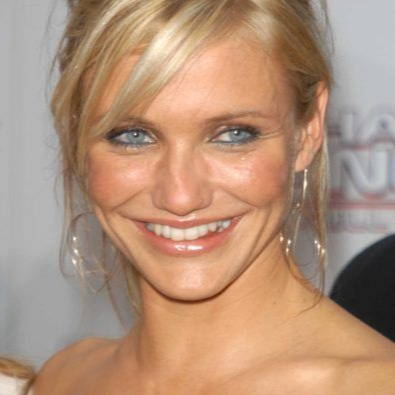 Smiling woman with blonde hair and blue eyes at a red carpet event.