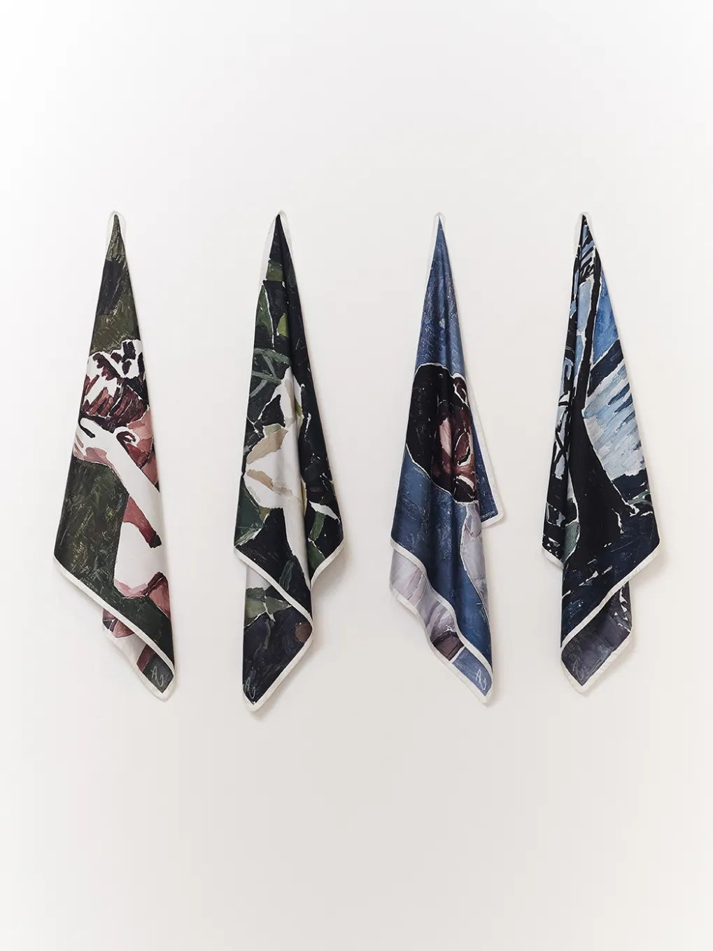 Three decorative towels hanging on a wall with various designs.