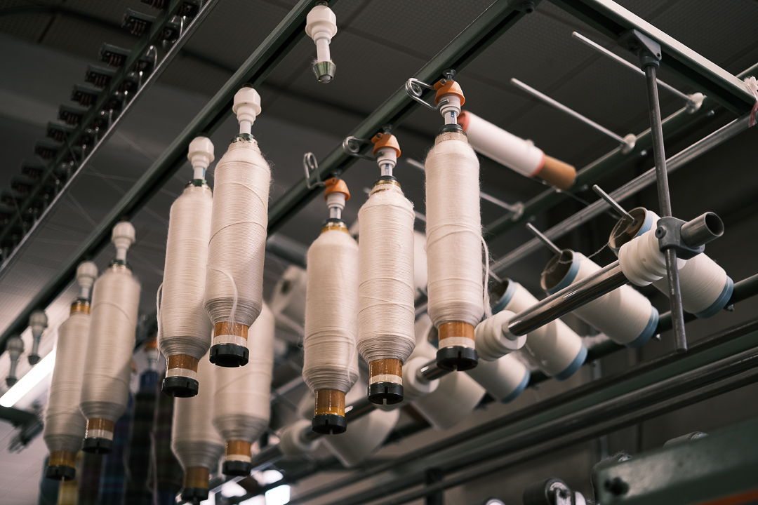 Spools of thread hanging on a manufacturing machine.