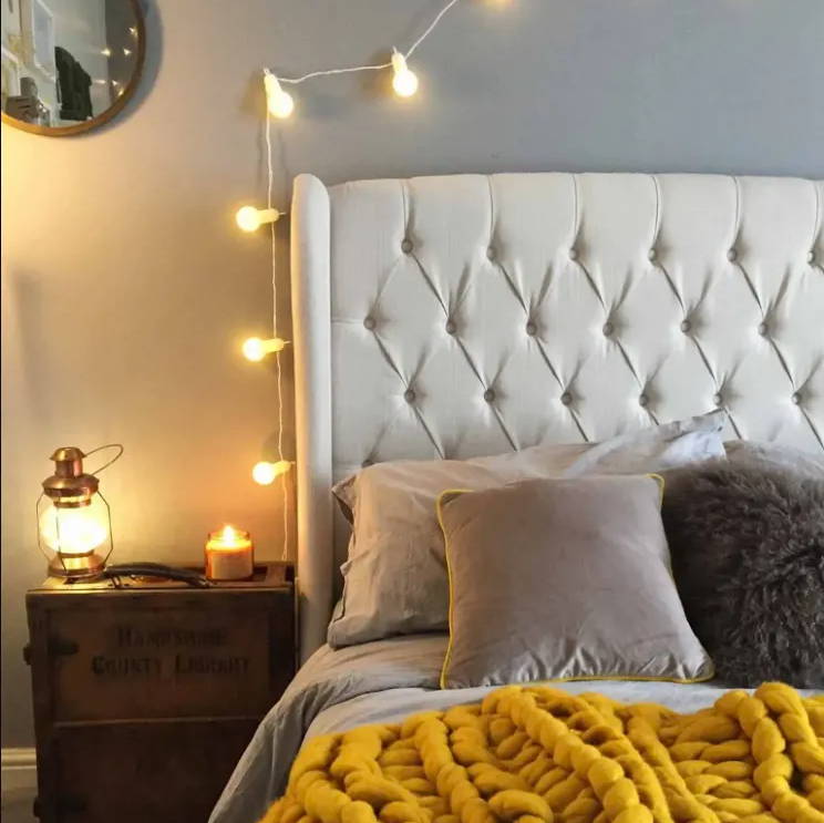 bedroom setting with a string of indoor fairy lights hung above the bed