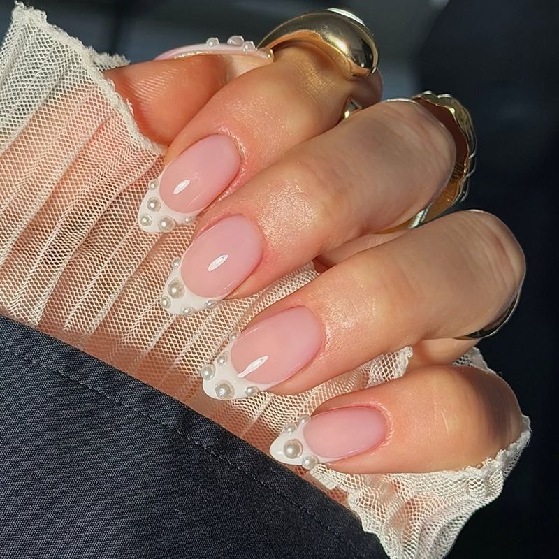 A hand with manicured nails featuring a pink base and white tips.