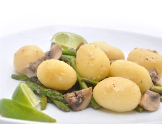 Boiled potatoes with asparagus, mushrooms, and lime on a white plate.