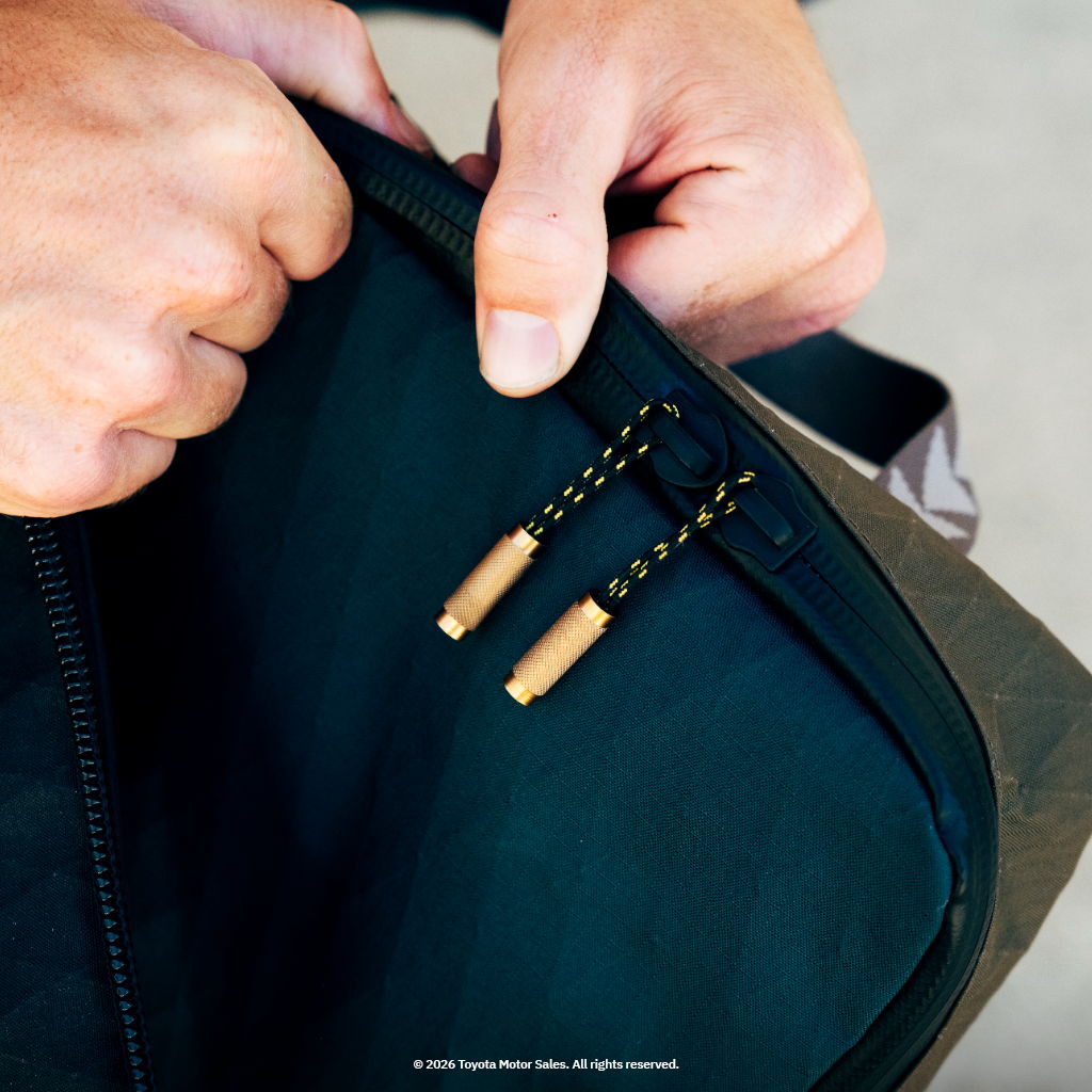 Person holding a bag with visible zippers and pull tabs.