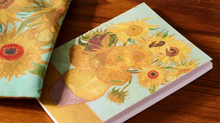 Notebook with a floral design featuring sunflowers on a wooden surface.