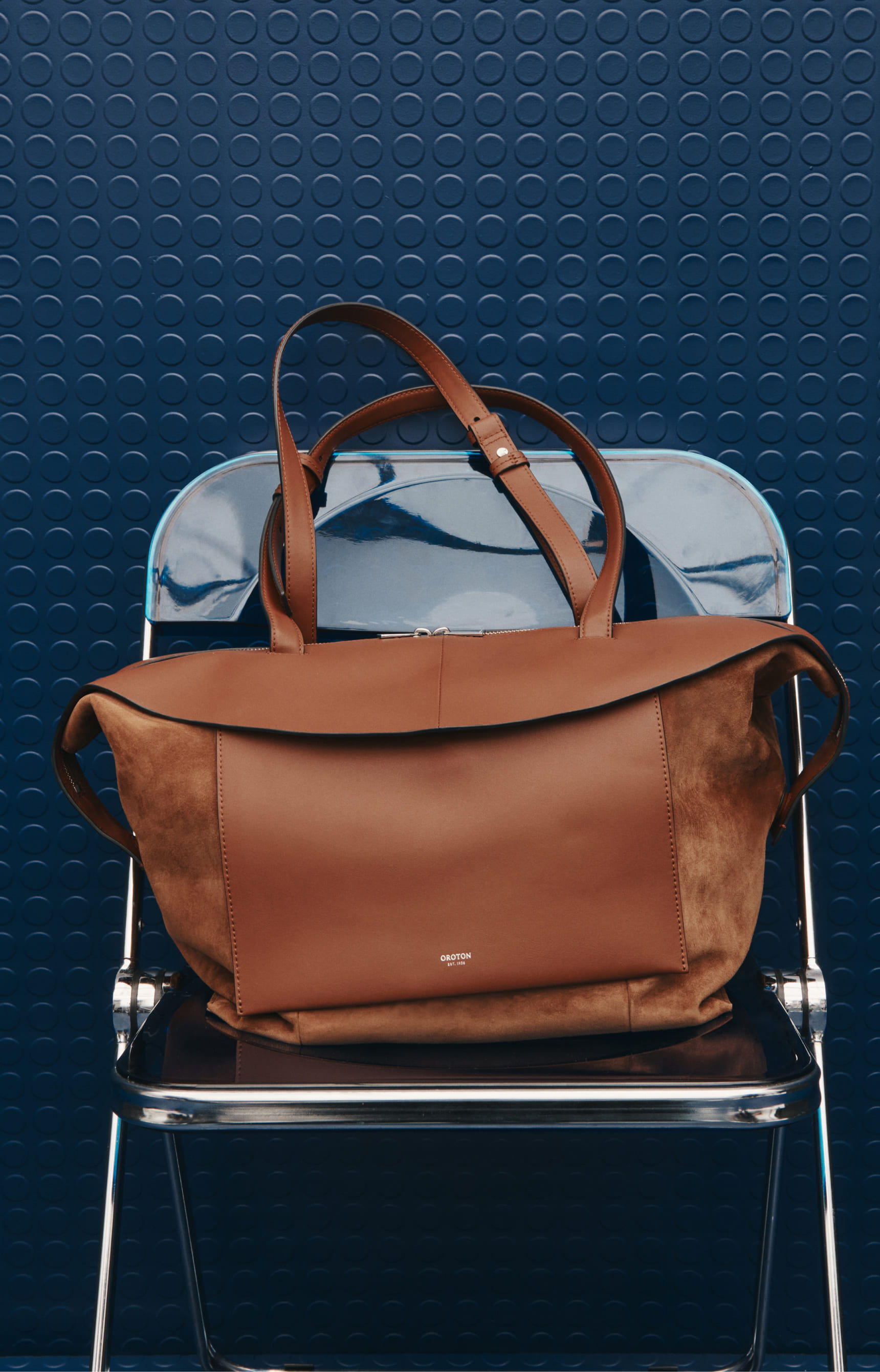 Brown bag resting on a blue chair against a textured blue background.