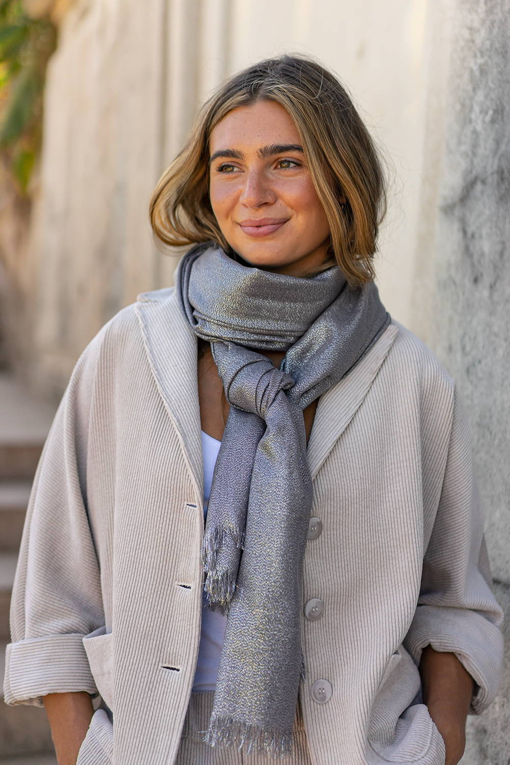 A model wearing a grey sparkly scarf and taupe corduroy jacket 