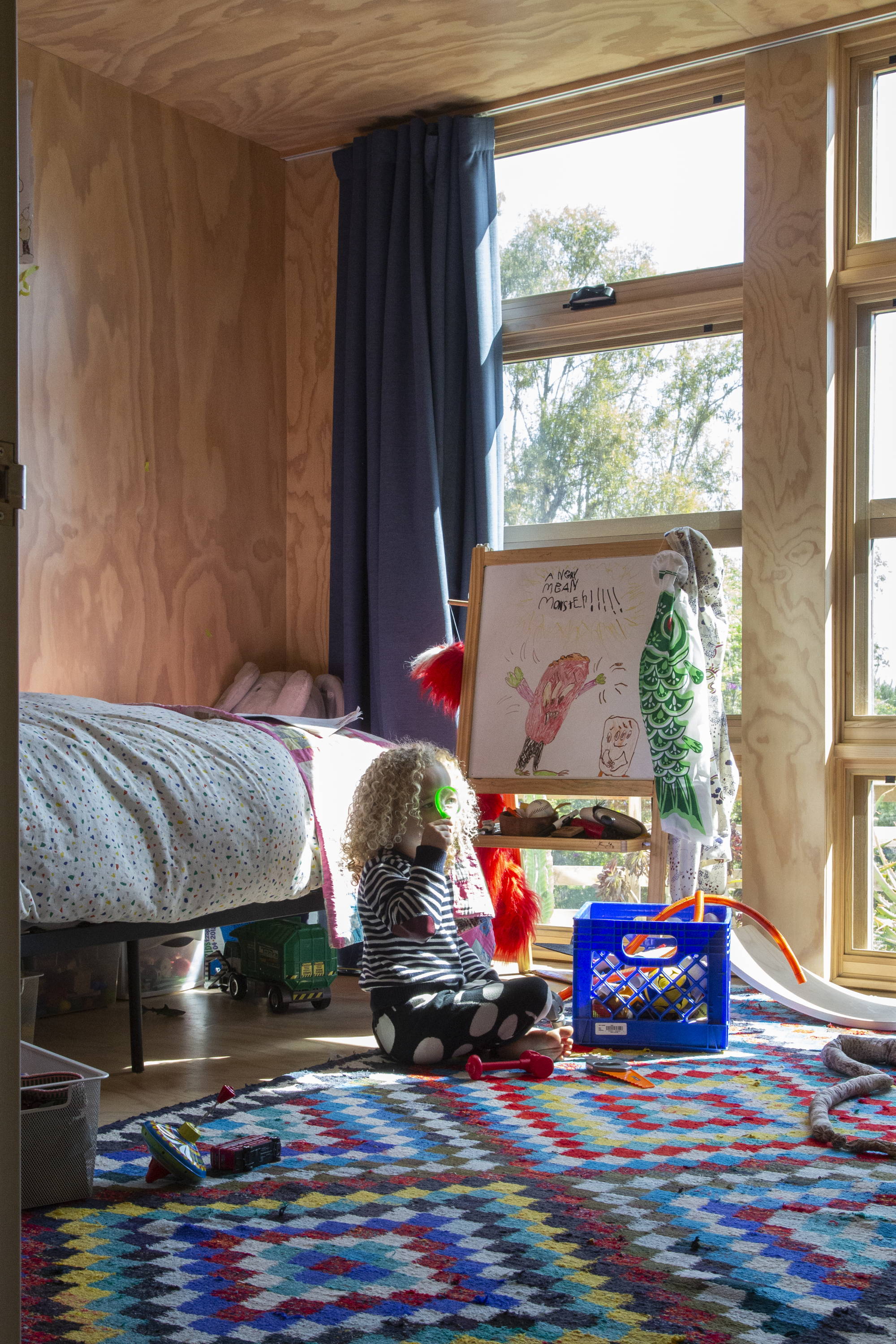 Child's room with wood walls, colorful rug, toys and single twin bed