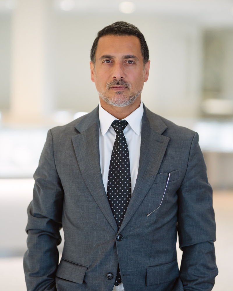 Man in a suit standing in a bright, modern office environment.