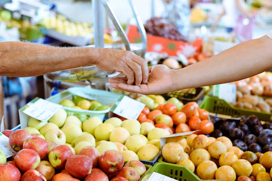 two arms exchanging money at a farmers market