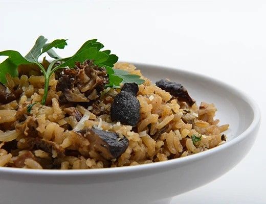 Bowl of rice with mushrooms and herbs.