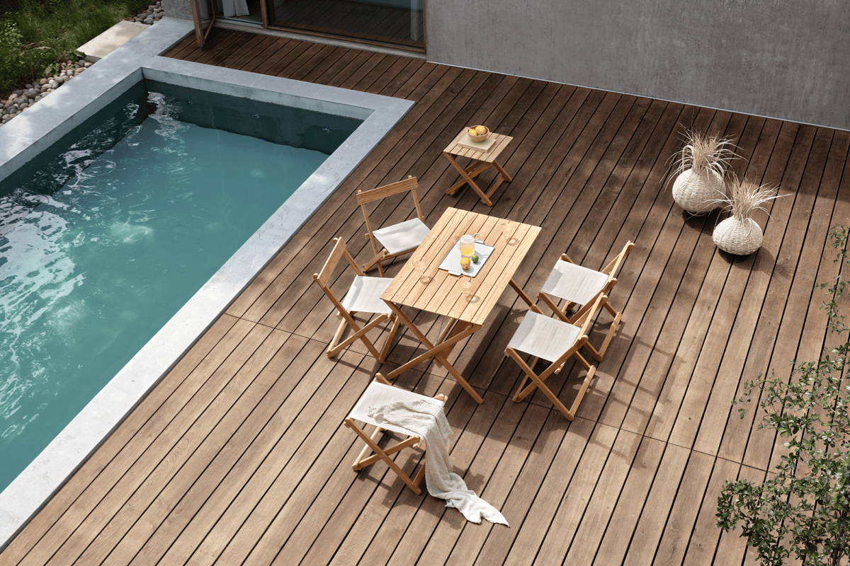 Boxhill's BM Teak Outdoor Foldable Table and foldable chairs on a poolside patio.