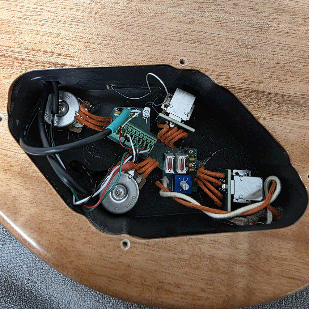 Internal components of an electric guitar, including wiring and circuit board.